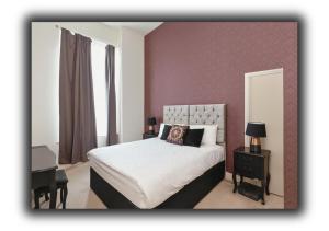 a bedroom with a white bed with a purple wall at The Vault Liverpool City Centre sleeps 4 in Liverpool