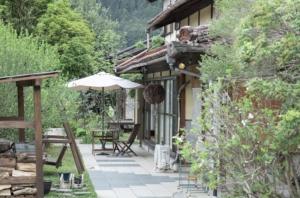 a patio of a house with an umbrella and chairs at cottonTSUKECHI in Nakatsugawa