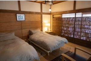 a bedroom with two beds and a window at cottonTSUKECHI in Nakatsugawa