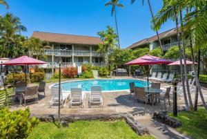 a resort pool with chairs and tables and umbrellas at Kona Islander Inn#228: Located in downtown Kona! in Kailua-Kona