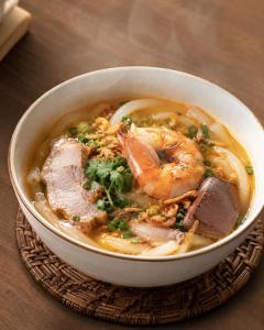 a bowl of soup with meat and vegetables on a table at Nam Hai Con Dao Hotel in Con Dao +43 photos