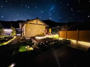 a house with a bath tub in the yard at night at 四季の庵 糸島 1300m2 大自然のパノラマ露天風呂 駐車場5台以上 サウナ 専用BBQ施設 ペット可 in Itoshima