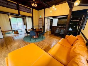 a living room with a yellow couch and a table at 四季の庵 糸島 1300m2 大自然のパノラマ露天風呂 駐車場5台以上 サウナ 専用BBQ施設 ペット可 in Itoshima +32 photos