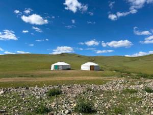 two white tents in a field with a green hill at Batzaya Herder Camp in Ulaanbaatar