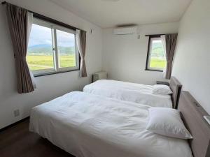 two beds in a room with two windows at ゲストハウス 華園 in Furano