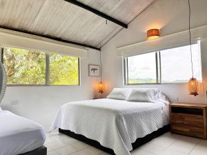 a bedroom with two beds and two windows at Isla Privada en Prado Piscina y Deportes Náuticos - Cerca a Bogotá - Cerca a Ibagué in Prado +58 photos