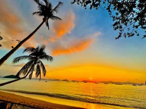 two palm trees on a beach at sunset at Doublegem Beach Resort and Hotel in El Nido