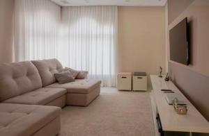 a living room with a couch and a tv at Quarto Aconchegante em Residência Familiar in São José