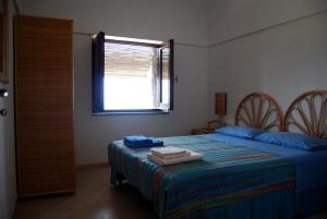 Un dormitorio con una cama con sábanas azules y una ventana. en Dammusi Punta Fram, en Pantelleria