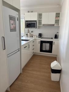 a kitchen with white cabinets and a white refrigerator at Apartment on Henry in North Ward