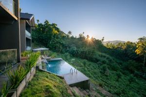 a house with a swimming pool on a hill with the sunset at Ella Lovers View Cabins in Ella