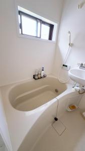 a white bathroom with a tub and a sink at 無料駐車場付き 広々一軒家を最大5名様に貸し出し 家禄亭 in Okayama