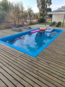a swimming pool on a wooden deck with two chairs at Cabaña Rincón de Colbùn in Colbún