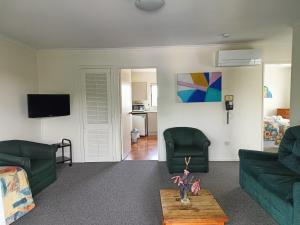 a living room with two green couches and a table at Raceway Motel in Christchurch