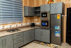 a kitchen with gray cabinets and a refrigerator at Edmundson Villa Apartment in Ejisu