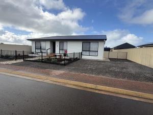 a small white house with a fence on the side of a street at Parsee Escape in Edithburgh