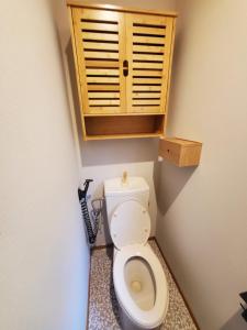 a bathroom with a toilet with a wooden cabinet at tomariel in Ō-shima