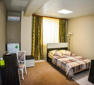 a bedroom with a bed and a window and a chair at Guest House Gamma in Khanty-Mansiysk
