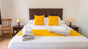 a bedroom with a bed with yellow pillows and towels at Hotel Boulevard del Río in Cali