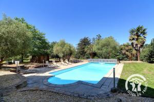 a swimming pool in a yard with trees at La grande maison in Orgères