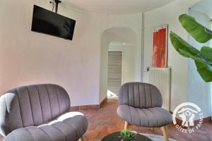 two chairs and a tv in a living room at Le moulin de la chicane in Orgères