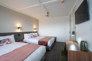a hotel room with two beds and a flat screen tv at Doonside Hotel, Blacktown in Doonside