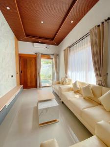 a living room with white furniture and a large window at The Res Village Lombok in Kuta Lombok +75 photos