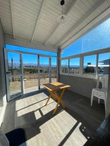 a screened porch with a wooden table and glass windows at Templanza in Villa Yacanto
