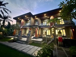 a large house with palm trees in front of it at Puri Bali Hotel in Lovina