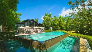 a swimming pool in front of a house at GREENHILLS RESORT Si Racha in Ban Nong Wa