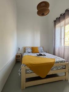 a bedroom with a bed with a yellow blanket on it at Casa Terra Odjo N'mar in Janela