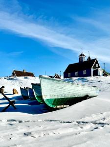 two boats sitting in the snow in front of a house at Kammak Hostel Sisimiut in Sisimiut +17 photos