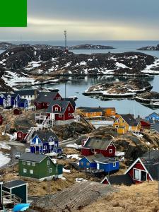 a group of houses on a hill with the ocean at Kammak Hostel Sisimiut in Sisimiut