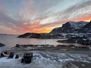 a truck parked in the snow near a body of water at Kammak Hostel Sisimiut in Sisimiut