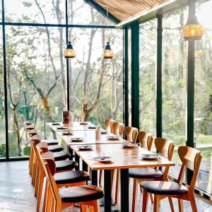 a long table and chairs in a room with windows at GREENHILLS RESORT Si Racha in Ban Nong Wa