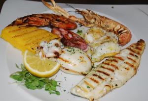 a plate of food with seafood and a lemon at Hotel Vela Velo Club Vieste in Vieste