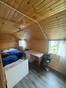 a bedroom in a wooden cabin with a bed and a desk at Gomismta Sky House in Gomi