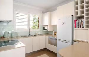 a white kitchen with a sink and a refrigerator at Lovley sunlit apartment walking distance to Cronulla mall and Cronulla Beach in Cronulla