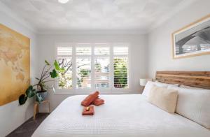 a white bedroom with a large bed and a window at Lovley sunlit apartment walking distance to Cronulla mall and Cronulla Beach in Cronulla