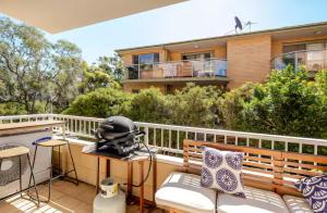 a balcony with a helmet on a table and chairs at Lovley sunlit apartment walking distance to Cronulla mall and Cronulla Beach in Cronulla