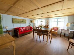 a living room with a red couch and a table at Revier Dorfidyll 1864 in Hätzingen +14 photos