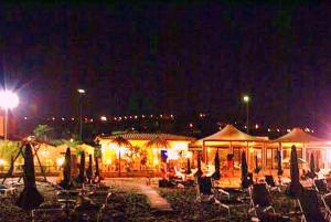 a group of chairs and umbrellas at night at Hotel Vela Velo Club Vieste in Vieste
