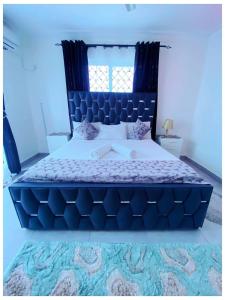 a blue bedroom with a large bed with a blue headboard at Nyali Glam Apartment in Mombasa