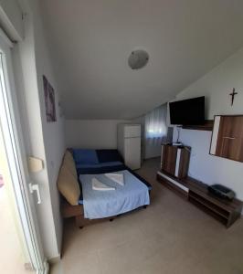 a small bedroom with a bed and a television at Mara apartman in Košljun