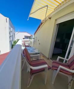 a balcony with two chairs and an umbrella at Mara apartman in Košljun