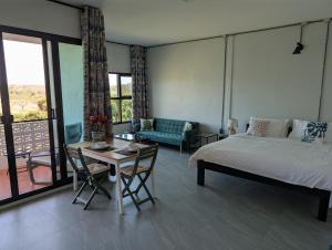 a bedroom with a bed and a table and a couch at Loei Valley Farm Stay in Wang Saphung
