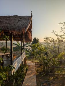 a building with a straw roof with a view of the countryside at Loei Valley Farm Stay in Wang Saphung