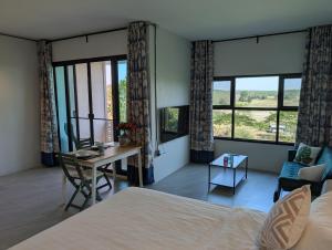 a bedroom with a bed and a desk and windows at Loei Valley Farm Stay in Wang Saphung