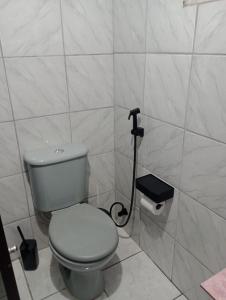 a white bathroom with a toilet and a black plunger at Rua da Expo Itaguaí in Itaguaí