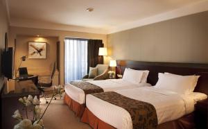 a hotel room with two beds and a desk at Jianguo Hotel in Beijing